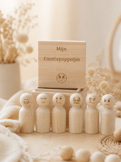 Set houten emotiepoppetjes met verschillende gezichtjes bij een gegraveerd bewaardoosje en een sfeervolle achtergrond.