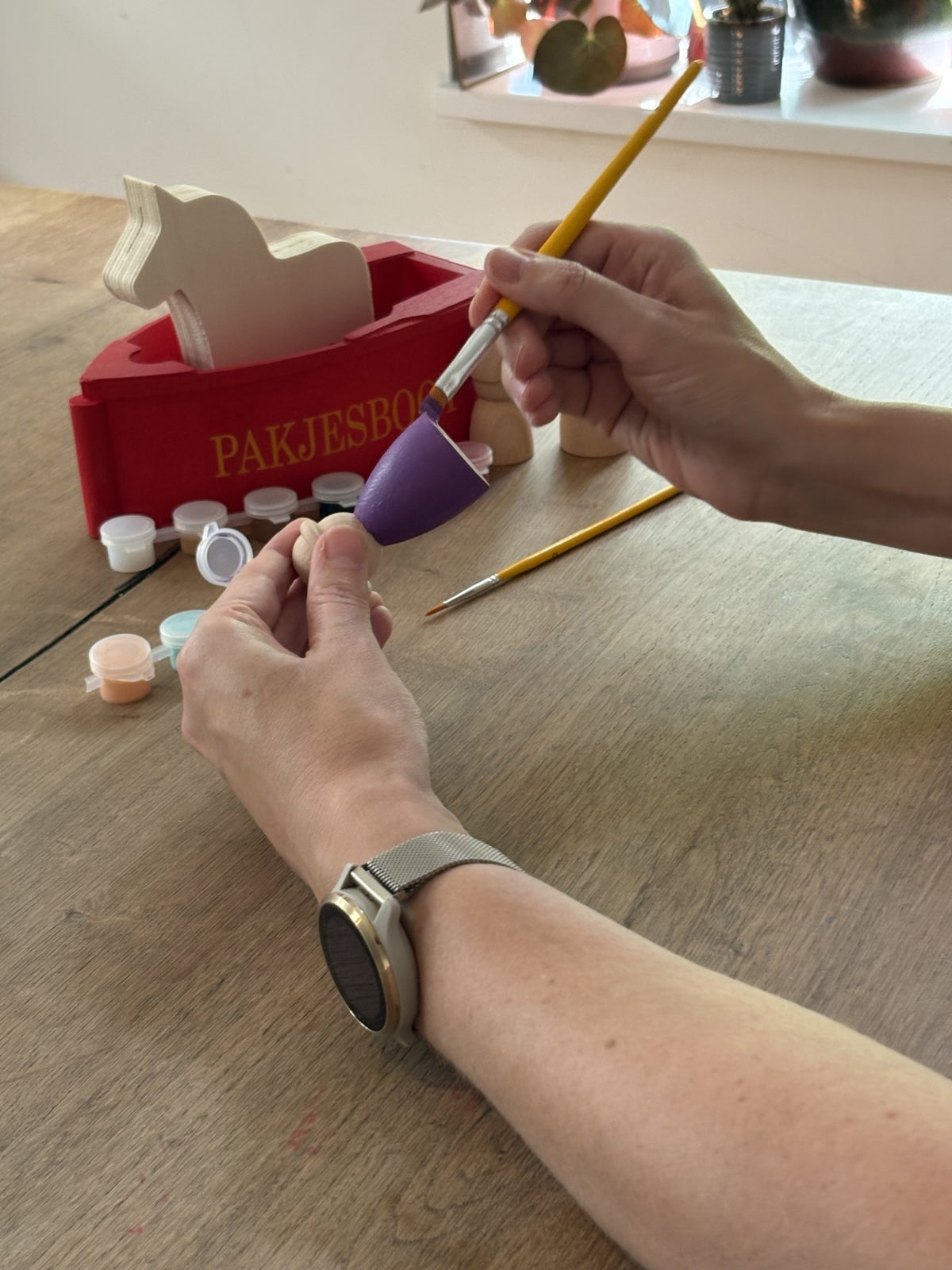 Handen die pietje paars schilderen die hoort bij een DIY knutselset van Sinterklaas.